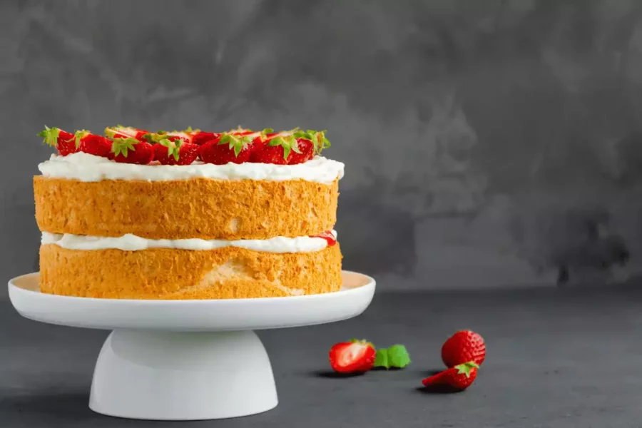 beyaz sunumluk üzerinde krema ve pasta ile hazırlanmış çilekli pasta